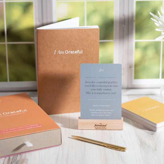 I Am Grateful gratitude journal and 52-card prompt set on a wooden stand, styled on a table by a window.