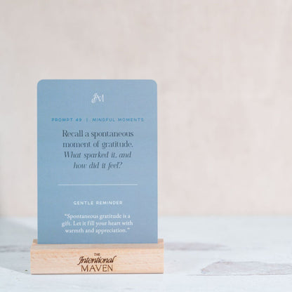 A single I Am Grateful prompt card on its minimalist wooden stand on a table.