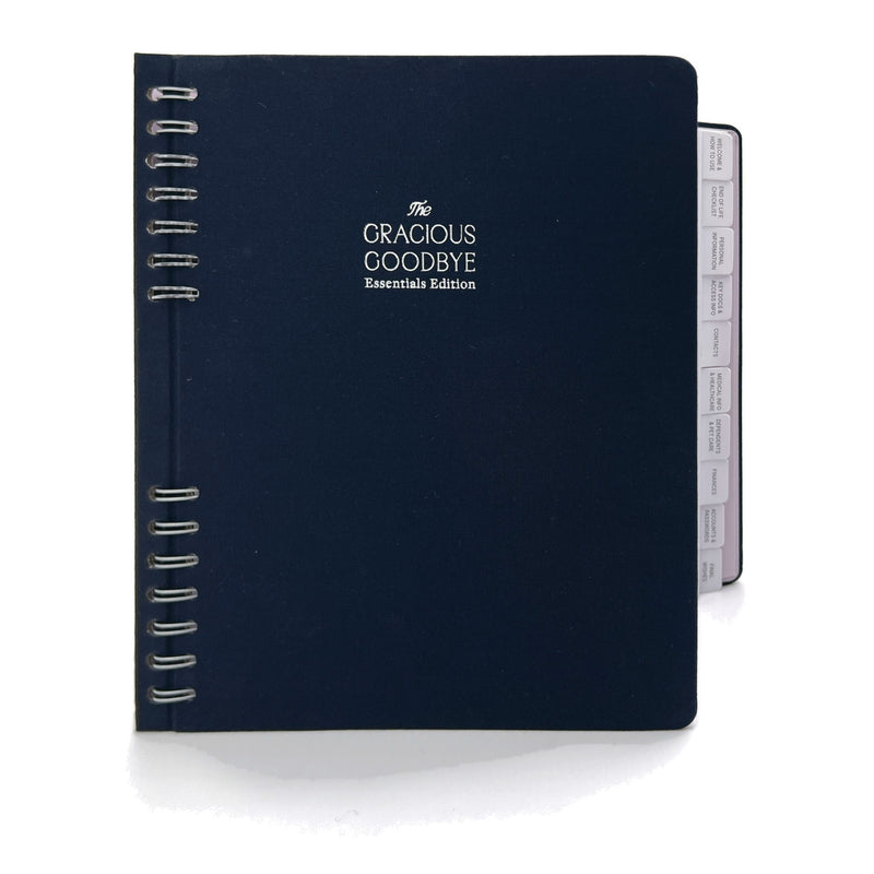 The Gracious Goodbye Essentials planner in navy linen, closed, with its silver-foil title and half-hidden spiral.